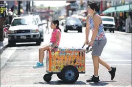  ?? Mel Melcon Los Angeles Times ?? ADRIAN VALDIVIA gives Acacia Valencia a ride on an ice cream cart Wednesday in downtown Los Angeles, which endured its third-hottest July on record.