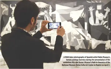  ??  ?? A MAN takes photograph­s of Spanish artist Pablo Picasso’s famed painting Guernica during the presentati­on of the exhibition Pity and Terror: Picasso’s Path to Guernica at the National Museum Reina Sofia Art Center in Madrid on April 3.