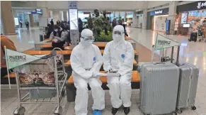  ?? AHN YOUNG-JOON/AP ?? Staffers with South Korea’s Chonnam National University wait at the airport in Incheon for Chinese students returning from holiday.