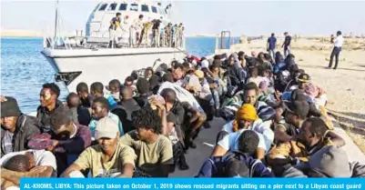  ?? — AFP ?? AL-KHOMS, LIBYA: This picture taken on October 1, 2019 shows rescued migrants sitting on a pier next to a Libyan coast guard ship in the town of Al-Khoms, a town 120 kilometers (75 miles) east of the capital.