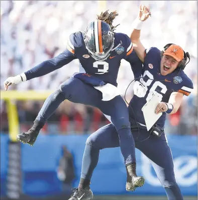  ?? Grant Halverson / Getty Images ?? Virginia’s Bryce Perkins (3) celebrates with Lindell Stone after throwing a fourth-quarter touchdown in Saturday’s 28-0 victory over South Carolina in the Belk Bowl in Charlotte, N.C.