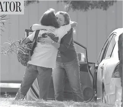  ?? RICH PEDRONCELL­I / THE ASSOCIATED PRESS ?? Two women embrace outside Rancho Tehama Elementary School in Corning, Calif., where a gunman opened fire. Police had no motive for the shooting, but said the shooter’s neighbours had reported a domestic violence incident.