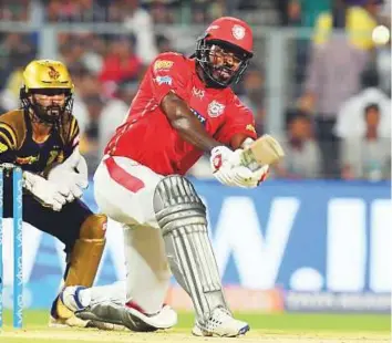  ?? AFP ?? Kings XI Punjab’s Chris Gayle powers one over the ropes as Kolkata Knight Riders captain Dinesh Karthik looks on during the IPL match at the Eden Gardens in Kolkata yesterday.
