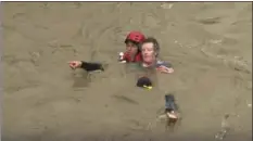  ?? KSBY-TV VIA AP ?? This photo from video provided by KSBY-TV shows a helmeted rescuer swimming with a man he is bringing out of the muddy, rain-swollen Salinas River in Paso Robles on California’s Central Coast on Thursday.