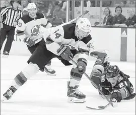  ?? Chris Carlson Associated Press ?? THE DUCKS’ Jake Dotchin, right, tries to get the puck from the Devils’ Miles Wood in Sunday’s game. The Ducks have won six of their last seven games.