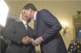  ?? ANDREW HARPER/GETTY IMAGES ?? President Donald Trump shakes hands with FBI Director James Comey during a Sunday White House reception for law enforcemen­t officers who worked the inaugurati­on.