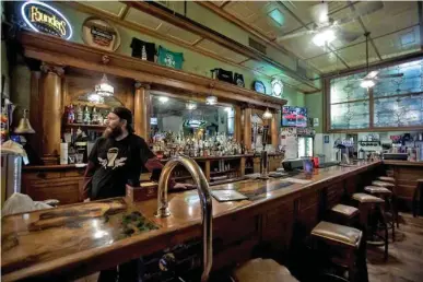  ?? STAFF PHOTOS BY TROY STOLT ?? Honest Pint bartender Cody Love stands behind an empty bar Tuesday. The Honest Pint decided to stay open for carryout service only on St. Patrick’s Day, normally one of the busiest days of the year for the bar.