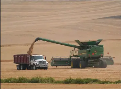  ?? (AP/Ted S. Warren) ?? A combine transfers wheat into a grain truck in early August near Pullman, Wash.