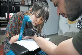  ?? RAHMAT GUL/AP ?? Suraya Shaheedi, 26, tattoos a customer in her mobile shop in Kabul, Afghanista­n.