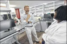  ??  ?? David Holland, chief clinical officer, talks to Cassandra Marquette, lab director, in the laboratory at the new Fulton County Public Health Clinic. The county facility has state-of-the-art lab equipment and private rooms that allow patients and staff to talk.