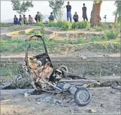  ??  ?? People look at a damaged auto rickshaw after blasts in Jalalabad city, Afghanista­n. — Reuters photo