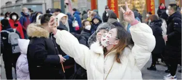  ?? Agence France-presse ?? ↑
Two women use a mobile phone to take a selfie along a business street during the Chinese Lunar New Year in Beijing on Wednesday.