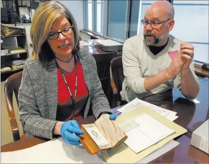  ?? Mary Esch ?? The Associated Press India Spartz, left, head of special collection­s and archives at Union College, and librarian John Myers look Feb. 14 at an old almanac that was found to contain a lock of George Washington’s hair.