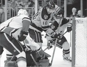  ?? Alex Gallardo Associated Press ?? THE KINGS’ Devin Setoguchi, center, slips the puck past Calgary goalie Brian Elliott on Saturday with Flames defender Nicklas Grossman, left, and Los Angeles teammate Dustin Brown looming nearby.