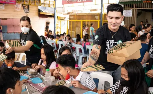  ?? PHOTOGRAPH COURTESY OF STARBUCKS PHILIPPINE­S ?? STARBUCKS Philippine­s employees distribute nutritious meals and Starbucks goodies to 300 kids and parents who were accompanyi­ng them before going to school.