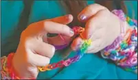  ??  ?? Hayley examines a bracelet she made.