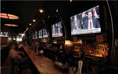  ?? (Joe Penney/Reuters) ?? PEOPLE WATCH former FBI director James Comey’s testimony before the Senate Intelligen­ce Committee on Thursday, in Tonic bar in New York City.