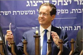  ?? OREN ZIV / AP ?? Israeli President Isaac Herzog lights candles during the Jewish holiday of Hanukkah in Hebron’s holiest site, known to Jews as the Tomb of the Patriarchs and to Muslims as the Ibrahimi Mosque, in the Israeli controlled part of the West Bank city of Hebron on Sunday.