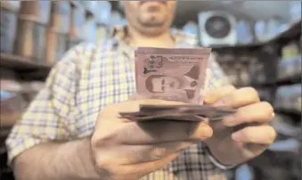  ?? -AFP ?? A merchant counts Syrian pound notes, bearing a portrait of the Syrian President Bashar Al Assad, at the Bzourieh market in the centre of the Syrian capital.