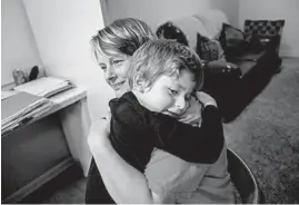  ??  ?? Gabriel, who does not speak but can sign a few words, hugs his mother, Laura Myers, before bedtime in their Centralia home.