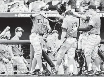  ?? Mike Theiler Associated Press ?? TIMMY RICHARDS (13) gets doused by Cal State Fullerton teammates after scoring on a third-inning hit by Taylor Bryant. The Titans led Vanderbilt, 3-0, in the sixth when play was stopped because of thundersto­rms.