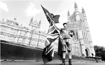  ?? — Reuters photo ?? A man holds an anti-Brexit banner on Westminste­r Bridge, in central London, Britain. British consumers appear little fazed by the possibilit­y of a no-deal Brexit, but businesses have turned more worried as business confidence in August fell six points to its lowest this year at 23 per cent, surveys showed.