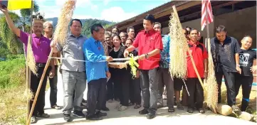  ??  ?? Dennis cuts the ribbon to declare open the cement road to the village as Juk (third left), Dominic (second left) and others look on.