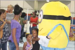  ??  ?? Kree and Khloe Middleton give hugs to a Minion from the “Dispicable Me” and “Minions” movies during Charles County Early Childhood Day at the Capital Clubhouse in Waldorf Saturday.