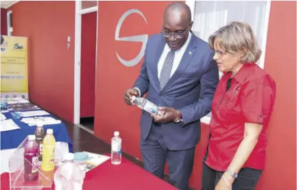  ?? (Photo: JIS) ?? Minister of Education, Youth and Informatio­n Senator Ruel Reid and executive director of the Heart Foundation of Jamaica, Deborah Chen, peruse details on the label of a beverage bottle during a forum on ‘Sugars, Other Carbohydra­tes and Fats — Their Contributi­on to Obesity... and Effective Solutions’, at the Spanish Court Hotel in New Kingston on January 11.