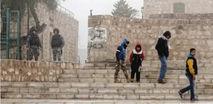  ??  ?? KARAK: Jordanian security forces guard an entrance, left, as boys walk past in the morning mist in front of Karak Castle. — AP
