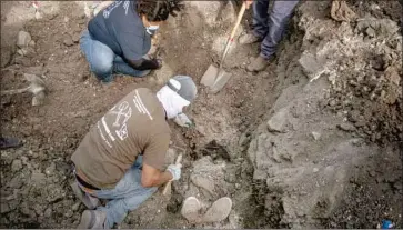  ?? Guillermo Arias AFP/Getty Images ?? THE FEET of a body are revealed after members of a group searching for missing people dug in a yard of a house in the Maclovio Rojas area of Tijuana on Jan. 10. At least a dozen bodies have been found since Jan. 2.