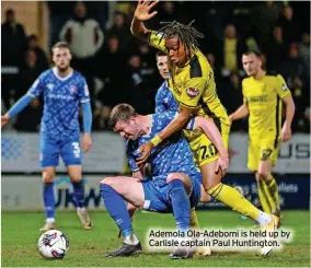  ?? ?? Ademola Ola-Adebomi is held up by Carlisle captain Paul Huntington.