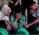  ?? ARMIN DURGUT/AP ?? Samed Alic, right, mourns with his family next to coffins containing the remains of his father, a victim of the Srebrenica genocide, on Monday in Potocari, Bosnia.