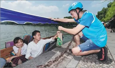  ?? NIU JING / FOR CHINA DAILY ?? An Eleme delivery man hands Starbucks coffee to tourists at the West Lake in Hangzhou, Zhejiang province.