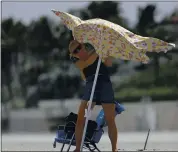  ?? WILFREDO LEE — THE ASSOCIATED PRESS ?? A beachgoer battles the wind as she tries to set up a beach umbrella Saturday in Palm Beach, Fla.