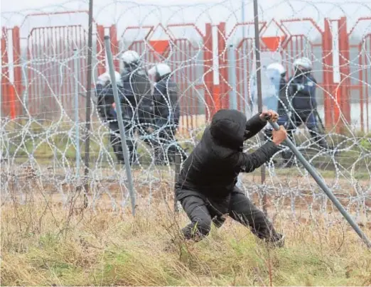  ?? // AFP ?? Un hombre intenta romper una valla al intentar cruzar la frontera