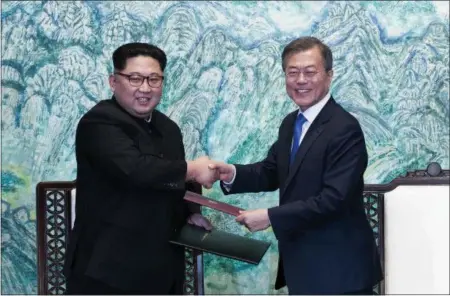  ?? KOREA SUMMIT PRESS POOL VIA AP, FILE ?? North Korean leader Kim Jong Un, left, and South Korean President Moon Jae-in shake hands after signing on a joint statement at the border village of Panmunjom in the Demilitari­zed Zone, South Korea, in this file photo.