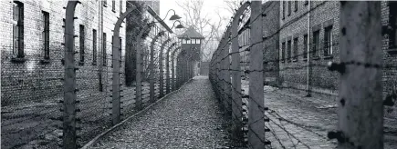  ??  ?? A pathway leads to an observatio­n and security tower between what were electric fences at Auschwitz I, which was built on an abandoned base.