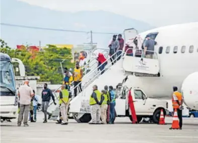  ?? EFE AFP ?? Agentes migratorio­s de EU y haitianos expulsados arriban en un avión a Puerto Príncipe