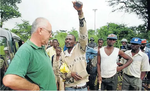  ?? Picture: Howard Burditt ?? The leader of a group of war veterans in Zimbabwe indicates where his followers will settle on Rockwell Farm, owned by farmer Andreo Malus, in Concession, 50km north of Harare, in March 2000. The Zimbabwe government now plans to pay compensati­on to white farmers who made improvemen­ts to land they previously owned.