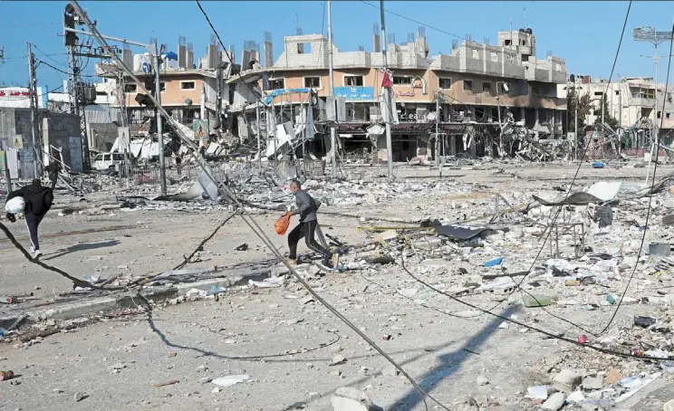  ?? ?? Palestinia­ns walking through destructio­n by the israeli bombardmen­t in the Nusseirat refugee camp in Gaza Strip. — ap