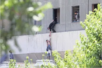  ?? OMID VAHABZADEH, GETTY IMAGES ?? Iranian police officers try to help civilians fleeing from the Parliament building during the attacks Wednesday in Tehran, Iran. Twelve people were killed and 30 wounded in the siege.