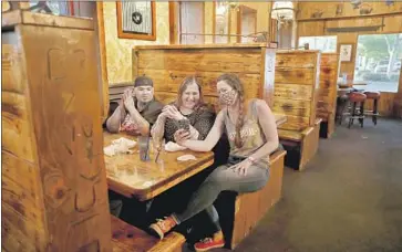  ?? Photograph­s by Gary Coronado Los Angeles Times ?? AT SILVER DOLLAR Saloon in Marysville, Calif., server Aimee Roux, right, mingles with customers Jeremiah Pino and Lydia Perez on Tuesday after Yuba County allowed businesses to reopen in defiance of the state.