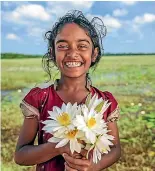  ??  ?? A little girl with lotus flowers in a lake near Sigiriya, Ceylon.