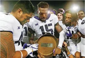  ?? [AP PHOTO] ?? TCU’s Ben Banogu (15); Izaih Filikitong­a, left; and Jaelan Austin, right, celebrate with the Iron Skillet trophy after a 42-12 victory over SMU last week.