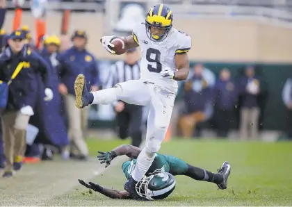  ?? GREGORY SHAMUS/GETTY IMAGES ?? Donovan Peoples-Jones of Michigan Wolverines catches a second-half touchdown pass and avoids the tackle of Michigan State’s Tre Person.