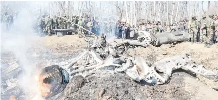  ??  ?? Indian soldiers and Kashmiri onlookers stand near the remains of an Indian Air Force (IAF) fighter jet after it crashed in Budgam district, some 30kms from Srinagar.