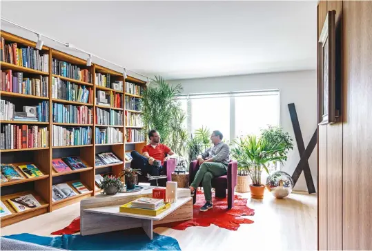  ??  ?? BELOW A custom teak library – by Ben Homes – spans the living room, shelving innumerabl­e volumes on art, design and photograph­y. Vintage rugs and marble coffee table; armchairs from The Bay; track lighting by Liteline.