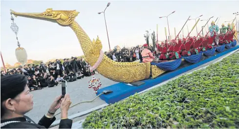  ?? PATIPAT JANTHONG ?? A woman takes a photo of naval officers performing a demonstrat­ion procession of the ‘Suphannaho­ng’ Royal Barge with a craft mock-up during an event to pay tribute to the late King.
