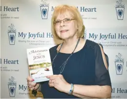  ?? MARY COMPTON/DAILY SOUTHTOWN ?? Diane Carroll, of Lockport, holds a book she wrote titled “Adventures with Jesus: Celebratin­g 20 Years of Miracles and Blessings,” during a banquet late last month for My Joyful Heart.
